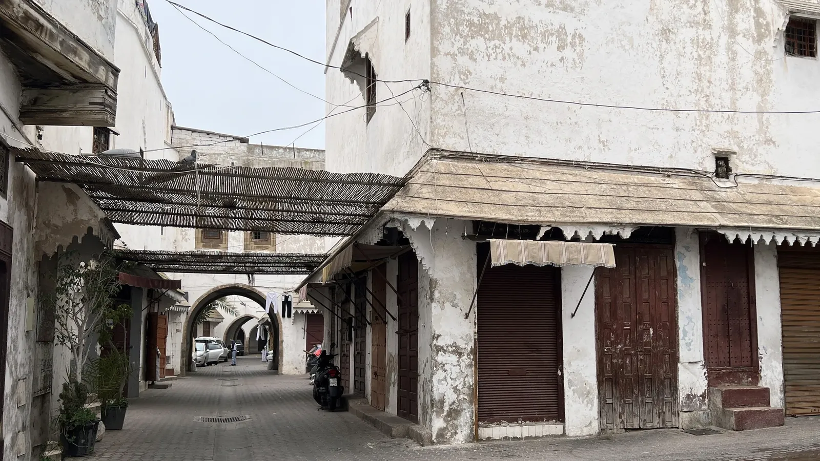 Whitewashed alley with reed awnings and traditional wooden shopfronts in the Habous Quarter, Casablanca