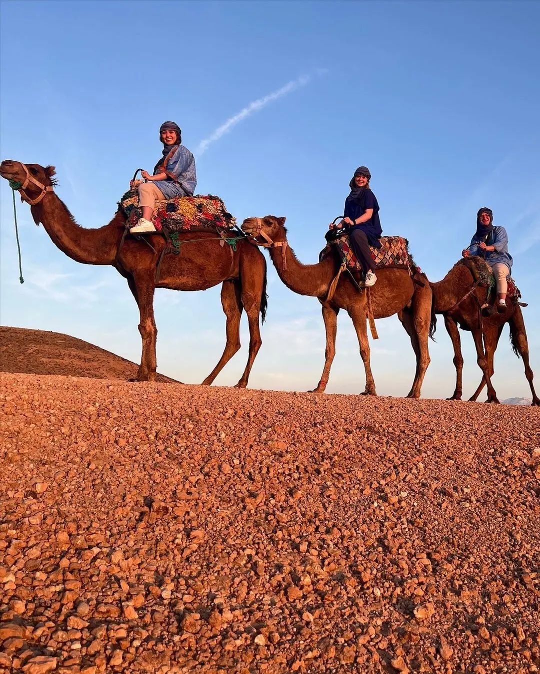 Tourists enjoying camel trek across Agafay Desert with guide in traditional Berber clothing