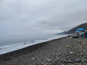 Discover Jnan Nich Beach, a hidden black sand paradise in northern Morocco. Crystal clear waters, dramatic cliffs, and authentic Berber culture await.